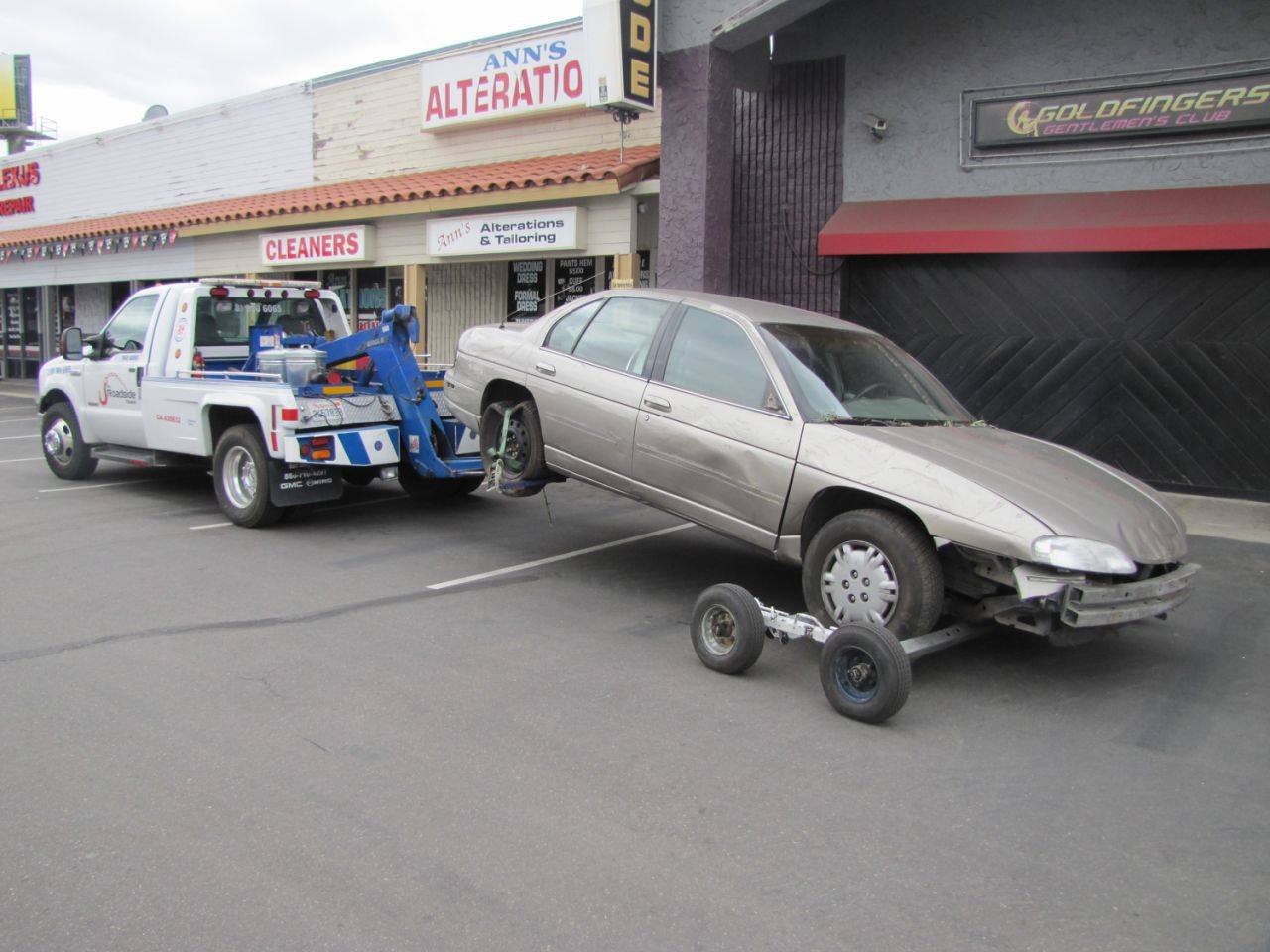 All Roadside Towing impounds a car at a business then loads it on dollies to haul it out.